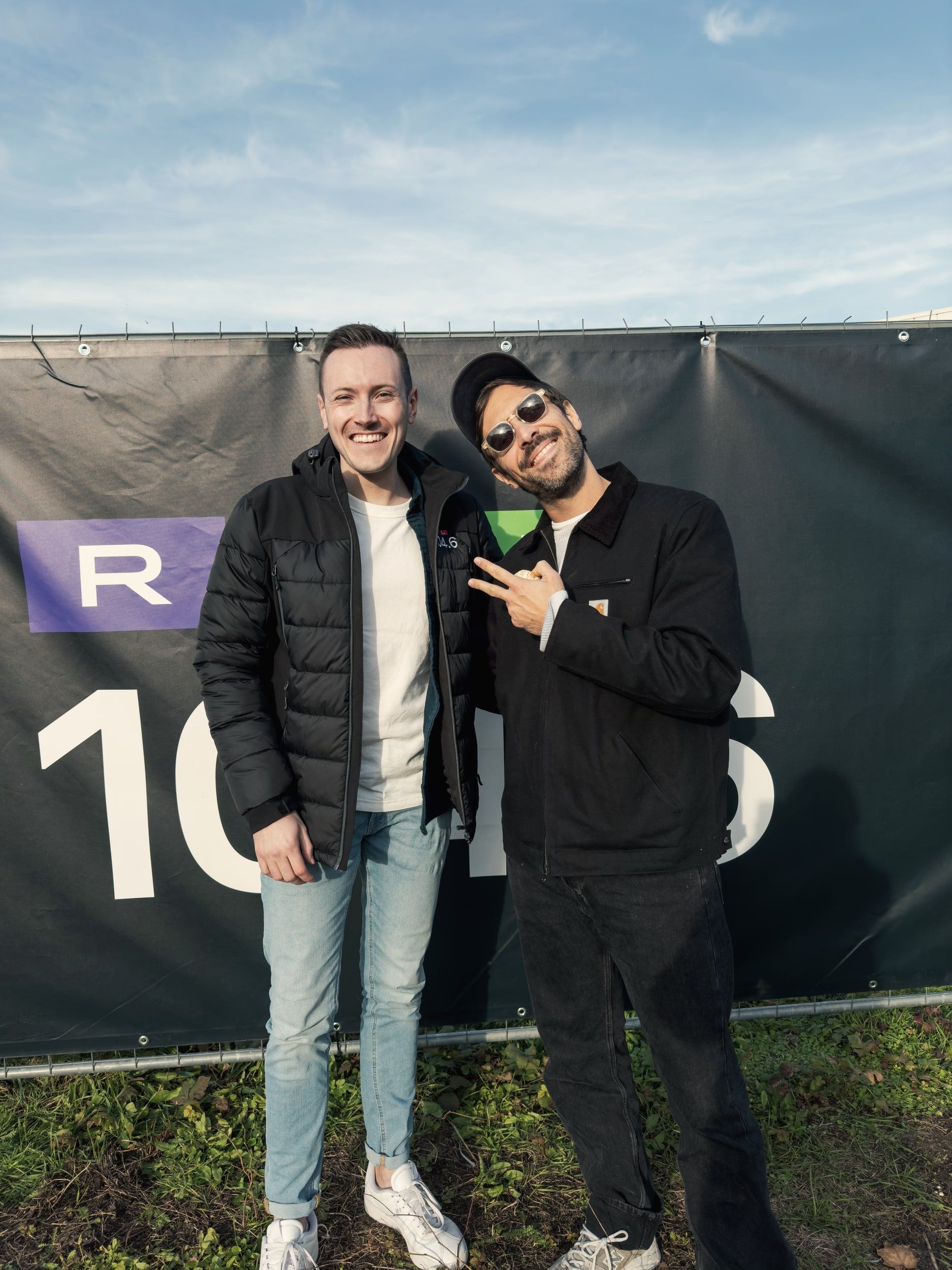 Chris Hartmann mit einem Gast vor einem Banner von 104.6 RTL